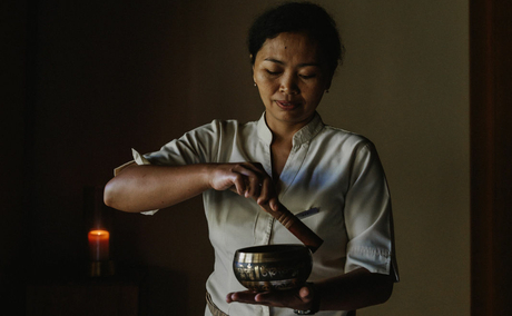 Amankila spa therapist pouring warm oil during treatment preparation.