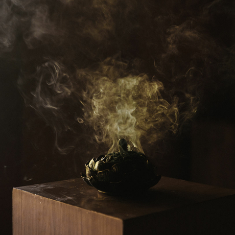 Amankila spa treatment featuring aromatic steam rising from a dark vessel on a wooden pedestal.