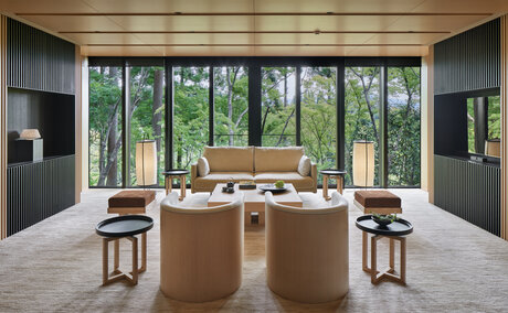 Aman Kyoto Suite with large windows overlooking garden, wooden desk, and minimalist furnishings.