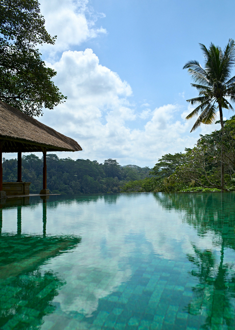 Amandari's swimming pool reflecting sky and tropical landscape, Indonesia.