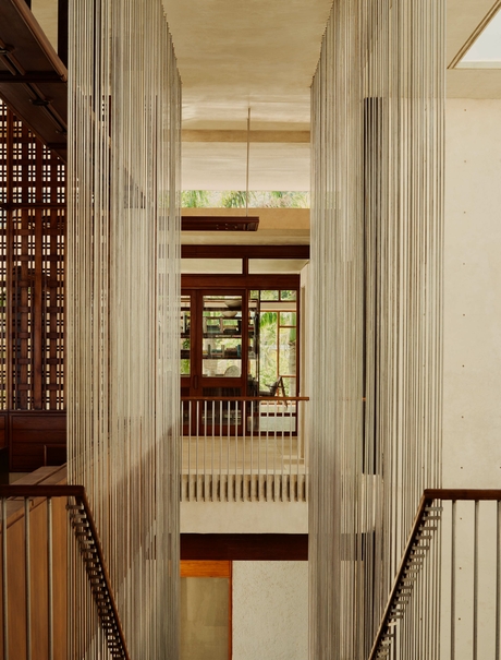 Amanera corridor with floor-to-ceiling cream curtains and wooden architectural details.