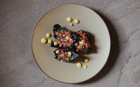 Grilled fish fillet with charred exterior and corn garnish on a cream plate at Amangani.