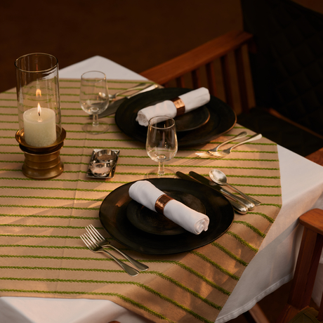 Private dining setup at Aman-i-Khas with candlelit table, place settings and wine in jungle setting.