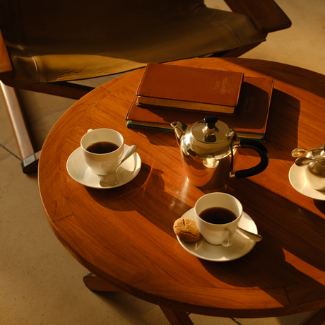Wooden table in Aman-i-Khas lounge tent with coffee cups and leather accessories.