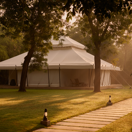 Wooden pathway leading towards a canvas tent at Aman-i-Khas, framed by trees at golden hour.