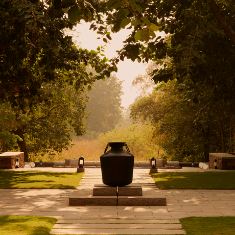 A central plunge pool at Aman-i-Khas framed by tree-lined pathways and dappled sunlight.