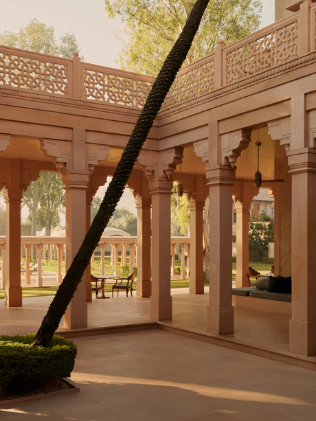 Amanbagh's main building exterior showing carved wooden screens and columns framing views of the courtyard gardens.