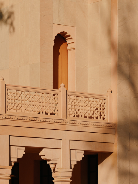 Amanbagh's main building exterior detail showing carved stone balcony with decorative lattice work and traditional architectural elements.
