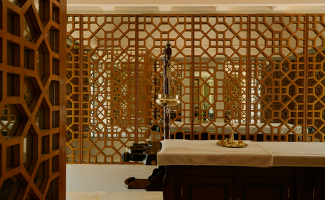 Spa treatment room at Amanbagh with ornate wooden lattice screens and stone bathtub.