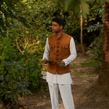 Doctor at Amanbagh wearing traditional terracotta waistcoat and cream robes amid lush garden pathways.