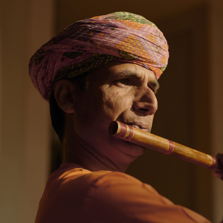 Musician playing a wooden wind instrument at Amanbagh, wearing traditional headwrap.