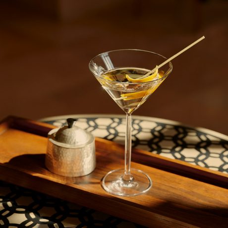 Cocktail served in a martini glass at Amanbagh's bar, with a stirrer and warm-toned backdrop.