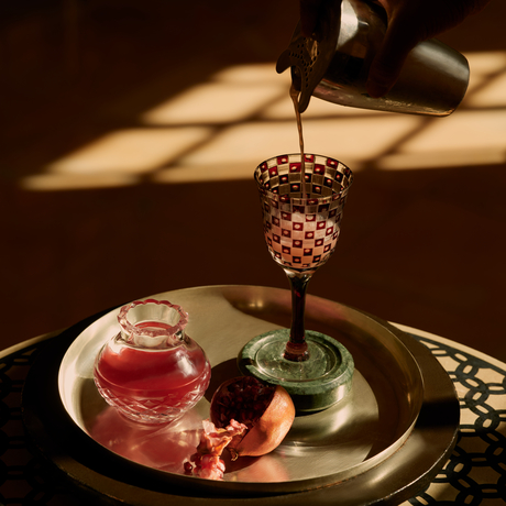 Bar detail at Amanbagh showing cocktail being poured over ice in a geometric glass.
