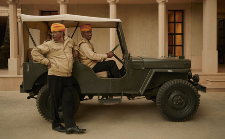 Group of staff members gathered around a vintage military jeep at Amanbagh.