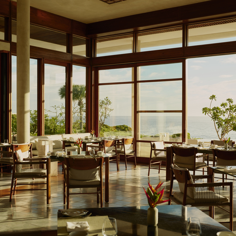 Amanera dining room with wooden tables and chairs overlooking tropical gardens through expansive windows.