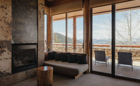 Deluxe Suite at Amangani with fireplace, seating area, and expansive windows overlooking mountain landscape.