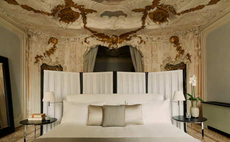 Alcova Tiepolo Suite principal bedroom at Aman Venice, featuring ornate ceiling frescoes and a canopied bed.