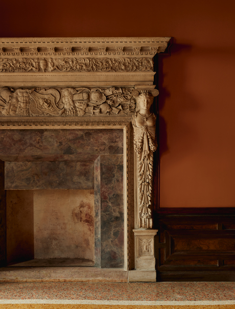 Ornate stone fireplace with classical detailing in a Venetian bedroom at Aman Venice.
