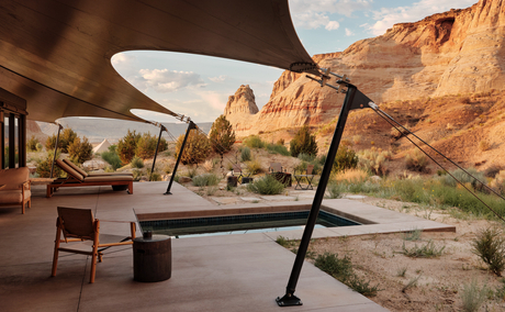 Outdoor terrace at Amangiri with views of red rock formations, featuring shaded seating area and desert landscape.