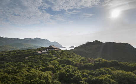 Verdant valley landscape at Amanoi with forested mountains beneath clouded sky.