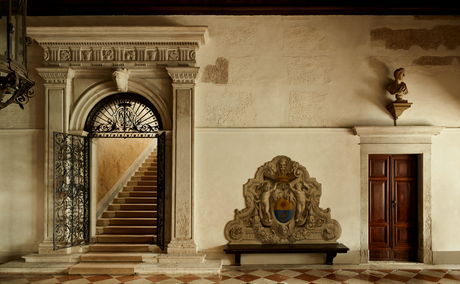 Ornate arched doorway and sculptural relief on the cream-coloured entrance wall at Aman Venice, Italy.