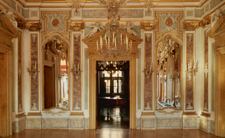 Ornate ballroom at Aman Venice with gilded columns, classical statues, and coffered ceiling.