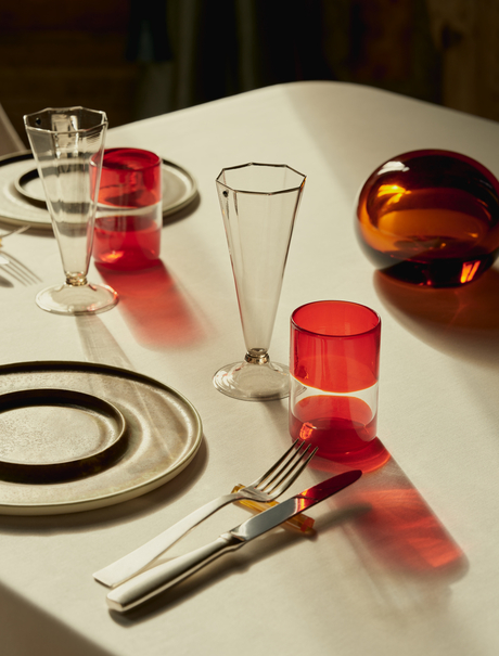 Chef Aman prepares an elegant dining table at Aman Venice, with coloured glassware and place settings by candlelight.