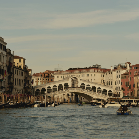 Rialto Bridge spanning the Grand Canal at Aman Venice, with historic Venetian palaces lining the waterfront.