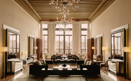 Fourth-floor reception room at Aman Venice with soaring ceilings, arched windows, and symmetrical seating areas.