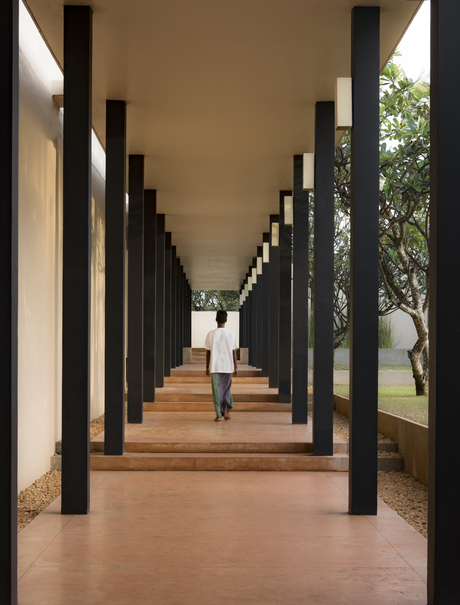 Covered walkway with black columns at Amanwella, Sri Lanka resort, leading towards natural light.