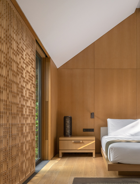 Amanyangyun bedroom with wooden panelling, brick accent wall and bed with white linens.