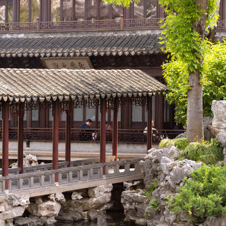 Traditional Chinese pavilion with dark timber framing at Amanyangyun, stone bridge and garden in foreground.