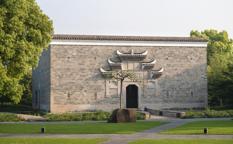 Traditional stone gatehouse at Amanyangyun, China, with curved roof detailing and manicured grounds.