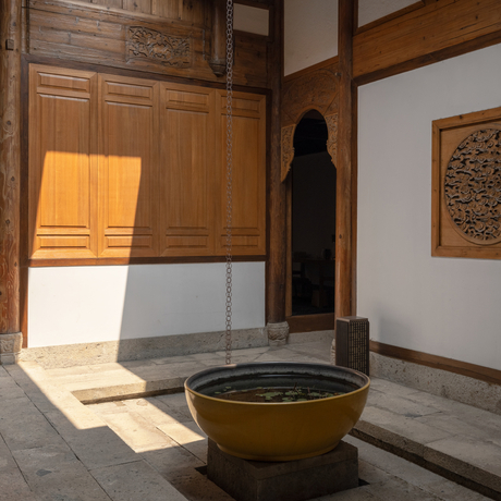 Sunlit courtyard at Amanyangyun with wooden doors, brass bowl, and traditional Chinese architectural details.
