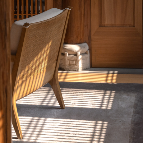 Sunlight streams across a wooden chair and slate floor at Amanyangyun, casting geometric shadows through a doorway.