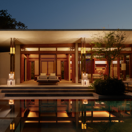 Amanera's evening exterior with illuminated pavilion reflected in still water at dusk.