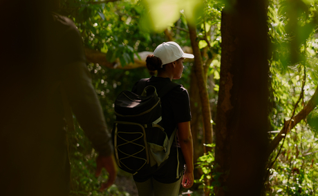 Forager with backpack walking through dense forest at Amanera.