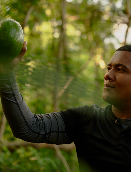 Forager at Amanera holding foraged ingredient amongst woodland greenery.