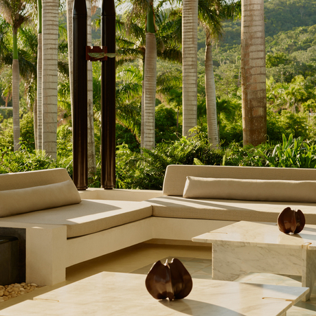 Amanera lobby with curved seating, wooden accents, and views of Dominican hillside through floor-to-ceiling windows.