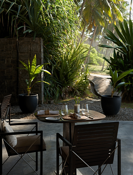 Garden dining area at Amanwella with potted plants and wooden table in Sri Lanka.