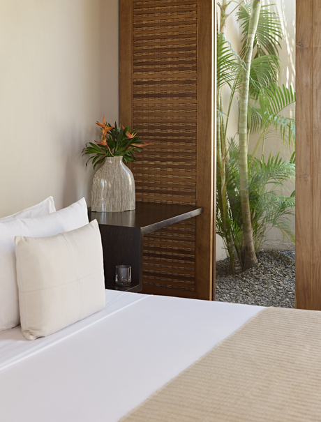 Suite bedroom at Amanwella with white bedding, wooden screen, and view of tropical greenery.