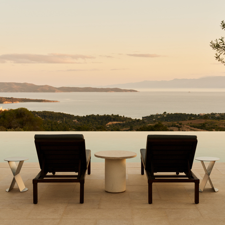 Villa terrace with two black chairs facing the Aegean Sea at sunrise, Amanzoe resort.