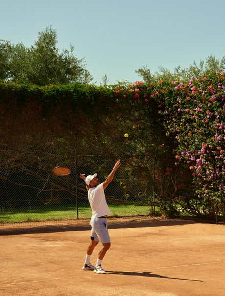 Player serving on the clay tennis court at Amanjena, Morocco.