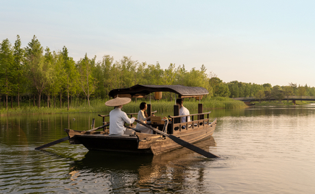 Afternoon tea served on a wooden boat at Amanyangyun, lakeside setting with forested shoreline.