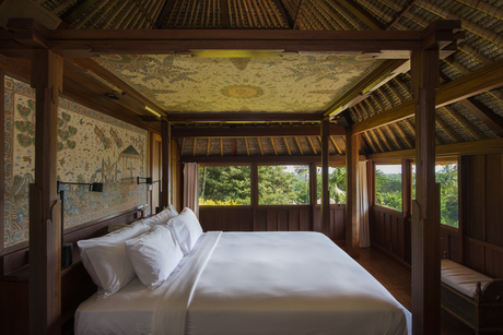 Ayung Suite bedroom at Amandari with bed facing open wooden doors overlooking the forest in Ubud, Bali.