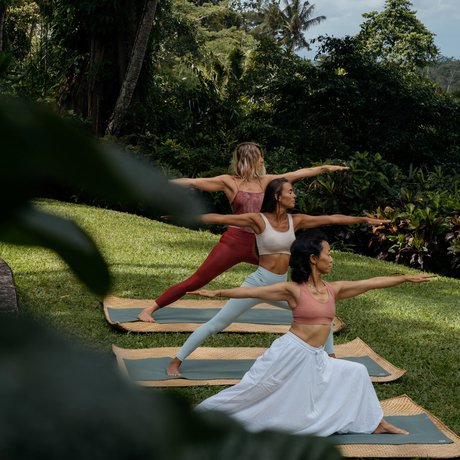 Two women practising yoga on mats in Amandari's lush garden grounds, Ubud, Bali.