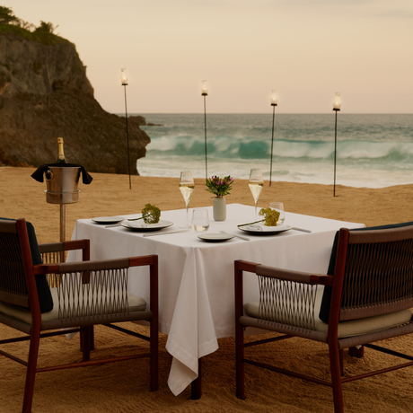 Beachfront dining table set for two at Amanera, with ocean views at sunset.