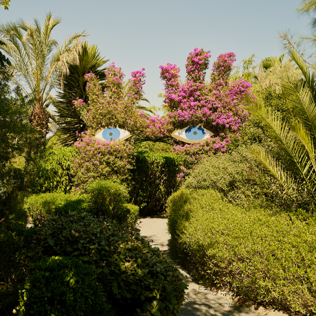 Lush garden at Amanjena with flowering bougainvillea, palm trees and manicured hedges in Morocco.