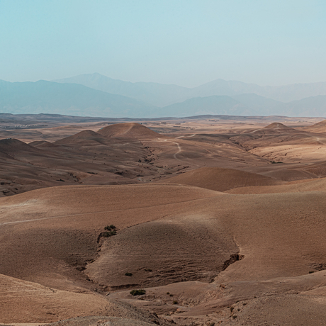 Expansive view of the Agafay Desert's rolling sandy dunes at Amanjena, Morocco.