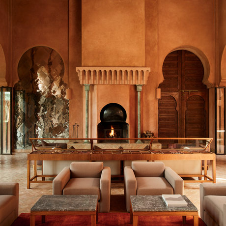Amanjena resort lounge with terracotta arches, carved wooden doors, and earthy seating areas in Moroccan architectural style.